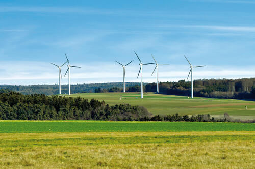 Sechs Windkraftanlagen in der Landschaft.