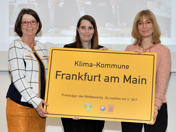 Umweltministerin Priska Hinz, Wiebke Fiebig (Energiereferat Frankfurt) und Dr. Kirsten Schröder-Goga (Regionalverband) halten den Preis - ein gelbes Schild mit der Aufschrift "Klima-Kommune Frankfurt am Main - Preisträgers des Wettbewerbs: so machen wir's - 2017" der Kamera entgegen.