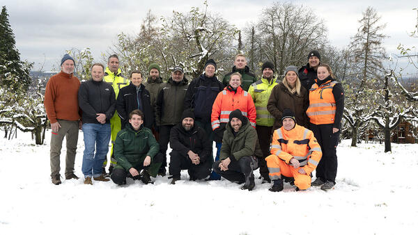 Drei Frauen und 14 Männer haben sich im Schnee für ein Foto aufgestellt.
