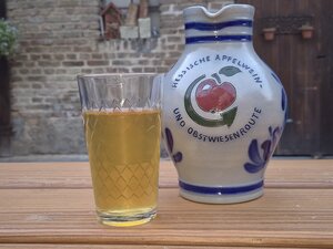 Geripptes Apfelweinglas und ein Bembel stehen auf einem Tisch