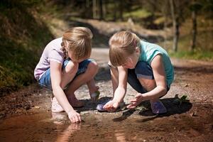 Zwei Mädchen erforschen eine Pfütze.
